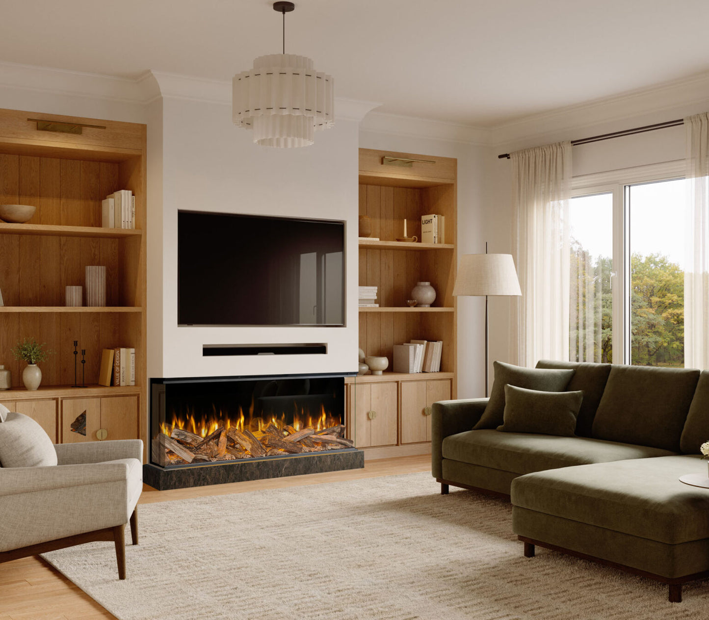 A modern living room featuring a built-in electric fireplace with a black frame and glowing logs, flanked by light wood built-in shelves. A green chaise lounge, a gray armchair, and a textured beige rug are arranged in front of the fireplace under a white tiered chandelier.